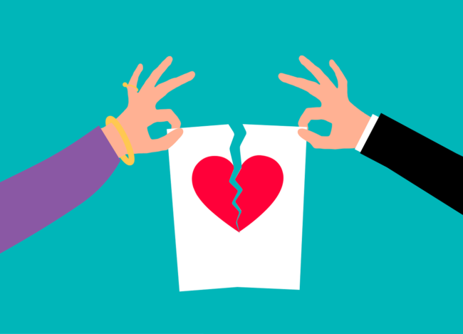 Dos personas rompiendo un papel con un corazón