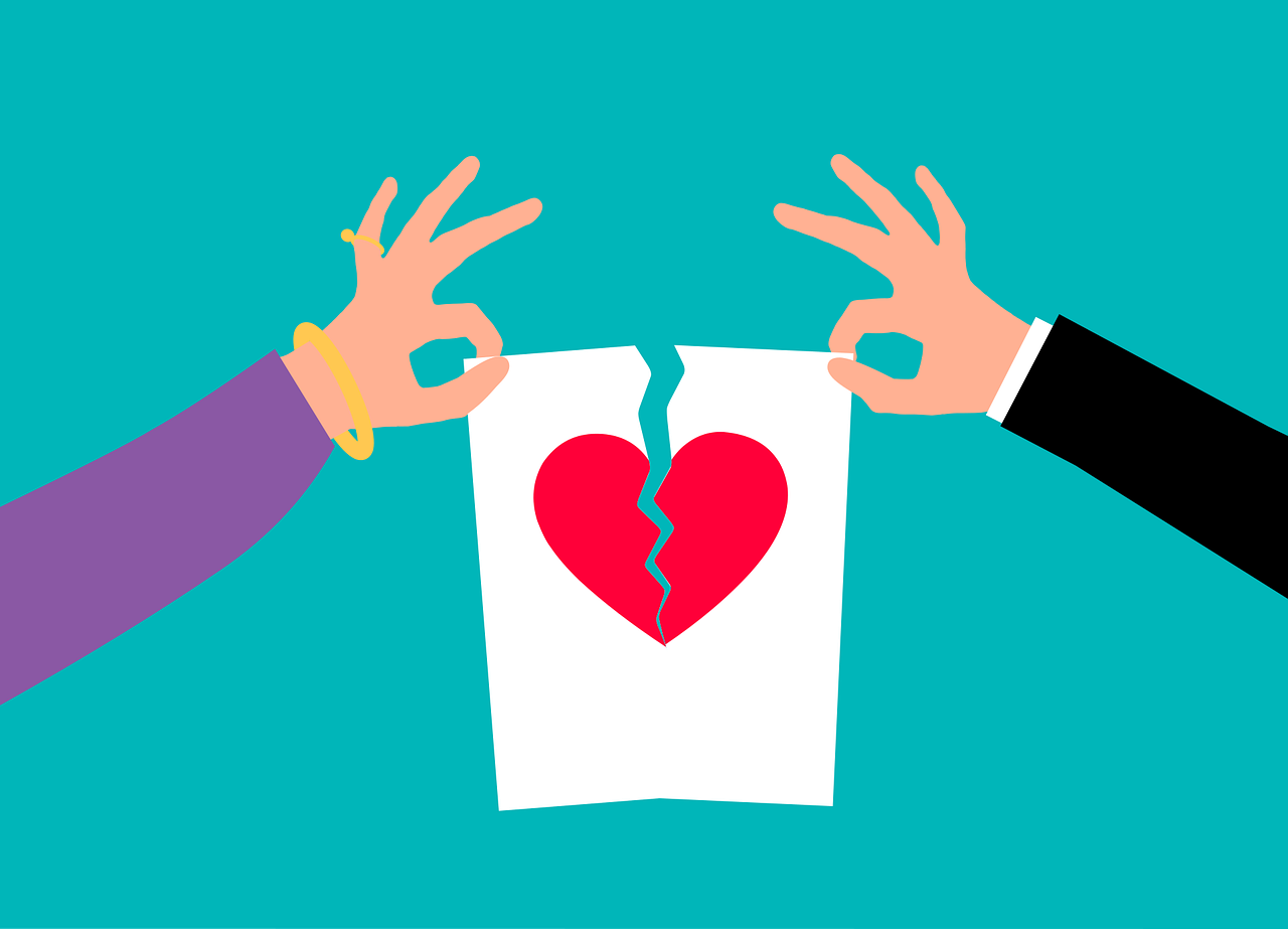 Dos personas rompiendo un papel con un corazón